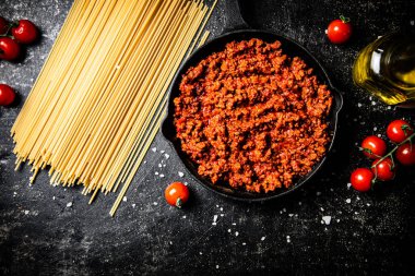 Tavada domatesli bolonez sosu ve kuru makarna. Siyah bir arka planda. Yüksek kalite fotoğraf