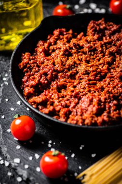 Taş bir tahtanın üzerinde domates, baharat ve kuru makarna ile bolonez sosu. Siyah bir arka planda. Yüksek kalite fotoğraf