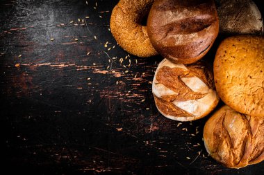 Masanın üzerinde çeşitli lezzetli ekmekler var. Karanlık bir arka plana karşı. Yüksek kalite fotoğraf