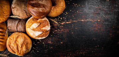 Masanın üzerinde çeşitli lezzetli ekmekler var. Karanlık bir arka plana karşı. Yüksek kalite fotoğraf