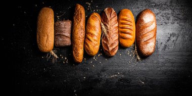 Masada farklı taze ekmek türleri var. Siyah bir arka planda. Yüksek kalite fotoğraf