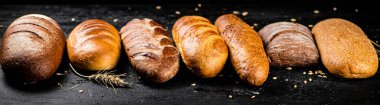 Masada farklı taze ekmek türleri var. Siyah bir arka planda. Yüksek kalite fotoğraf