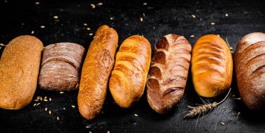 Masada farklı taze ekmek türleri var. Siyah bir arka planda. Yüksek kalite fotoğraf