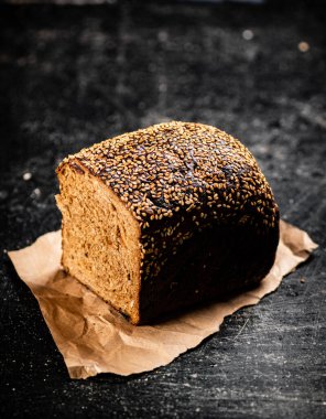 Kağıt üzerinde yarım somun ekmek. Siyah bir arka planda. Yüksek kalite fotoğraf