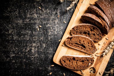 Kesme tahtasında dilimlenmiş çavdar ekmeği. Siyah bir arka planda. Yüksek kalite fotoğraf