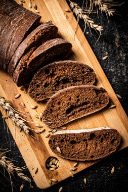 Kesme tahtasında dilimlenmiş çavdar ekmeği. Siyah bir arka planda. Yüksek kalite fotoğraf