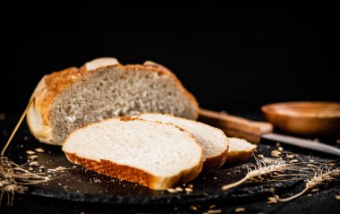Tahta bir tahtanın üzerinde tahıllı buğday ekmeği dilimlenmiş. Siyah bir arka planda. Yüksek kalite fotoğraf