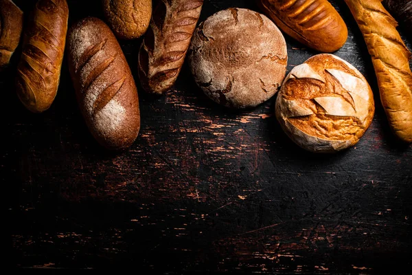Μια Ποικιλία Από Νόστιμα Ψωμί Στο Τραπέζι Ένα Σκοτεινό Φόντο — Φωτογραφία Αρχείου
