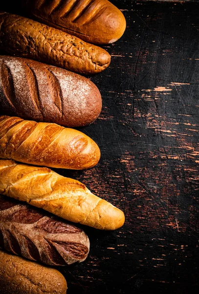 Μια Ποικιλία Από Νόστιμα Ψωμί Στο Τραπέζι Ένα Σκοτεινό Φόντο — Φωτογραφία Αρχείου