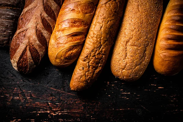 テーブルの上においしいパンの様々な 暗い背景を背景に 高品質の写真 — ストック写真