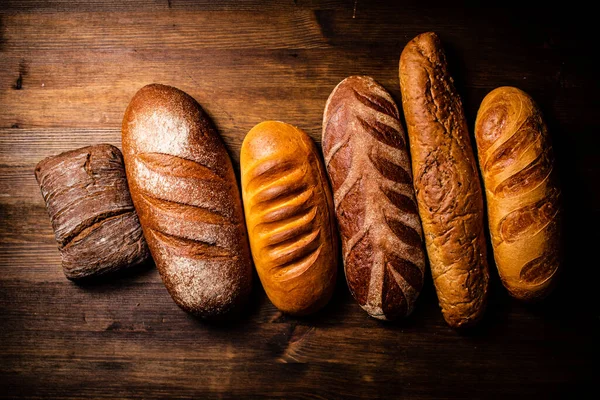 stock image Different types of freshly baked bread. On a wooden background. High quality photo