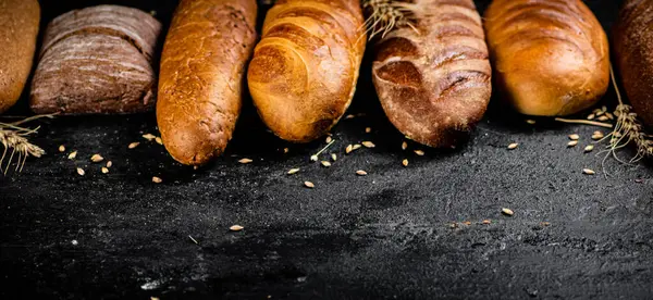 Διαφορετικοί Τύποι Φρέσκου Ψωμιού Στο Τραπέζι Μαύρο Φόντο Υψηλής Ποιότητας — Φωτογραφία Αρχείου