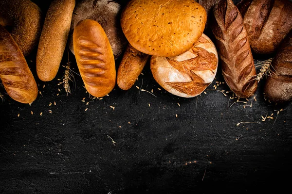 桌子上有不同类型的新鲜面包 在一个黑色的背景 高质量的照片 — 图库照片