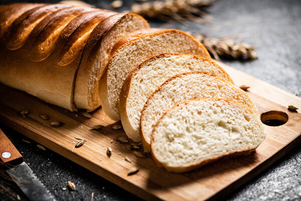 Sliced fresh wheat bread on a cutting board. On a black background. High quality photo