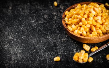 Tahta tabakta konserve mısır. Siyah bir arka planda. Yüksek kalite fotoğraf