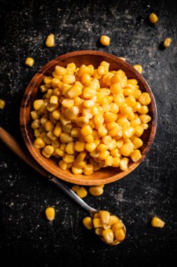 Tahta tabakta konserve mısır. Siyah bir arka planda. Yüksek kalite fotoğraf