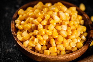 Tahta tabakta konserve mısır. Siyah bir arka planda. Yüksek kalite fotoğraf