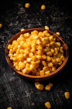 Tahta tabakta konserve mısır. Siyah bir arka planda. Yüksek kalite fotoğraf