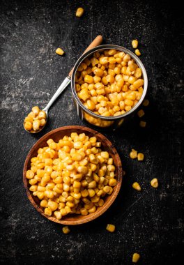 Tahta tabakta konserve mısır. Siyah bir arka planda. Yüksek kalite fotoğraf