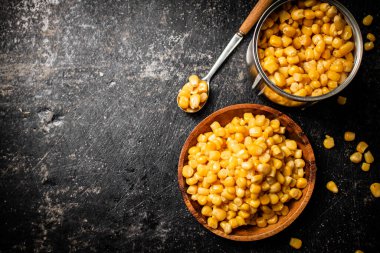 Tahta tabakta konserve mısır. Siyah bir arka planda. Yüksek kalite fotoğraf