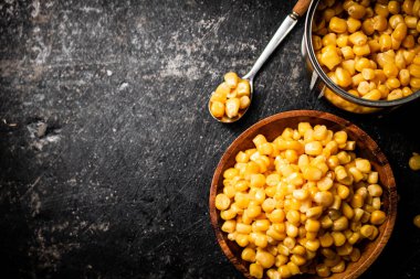 Tahta tabakta konserve mısır. Siyah bir arka planda. Yüksek kalite fotoğraf