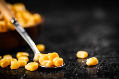 Bir kaşıkta konserve mısır taneleri. Siyah bir arka planda. Yüksek kalite fotoğraf