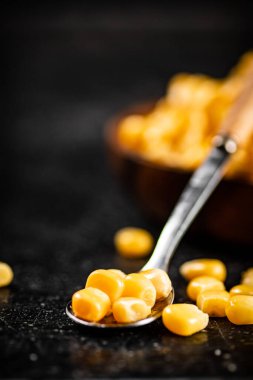 Bir kaşıkta konserve mısır taneleri. Siyah bir arka planda. Yüksek kalite fotoğraf