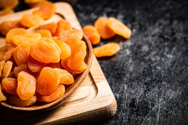 Kesme tahtasındaki bir tabakta kurumuş kayısılar. Siyah bir arka planda. Yüksek kalite fotoğraf