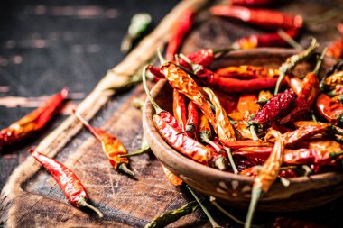 Kesme tahtasındaki tabakta kurutulmuş kırmızı biber. Karanlık bir arka plana karşı. Yüksek kalite fotoğraf