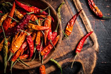 Kesme tahtasındaki tabakta kurutulmuş kırmızı biber. Karanlık bir arka plana karşı. Yüksek kalite fotoğraf