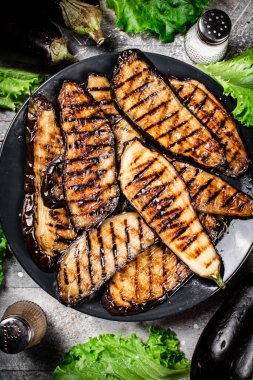 Bir tabak marulun üzerinde ızgara patlıcan. Gri bir arka planda. Yüksek kalite fotoğraf