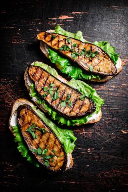 Kızarmış patlıcan ve marullu sandviç. Karanlık bir arka plana karşı. Yüksek kalite fotoğraf