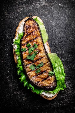 Masada ızgara patlıcanlı bir sandviç. Siyah bir arka planda. Yüksek kalite fotoğraf