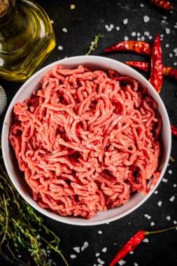 Acı biber kabuklarıyla dolu bir masada kasede kıyma. Siyah bir arka planda. Yüksek kalite fotoğraf