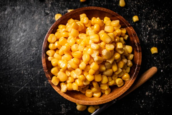 Canned corn on a wooden plate. On a black background. High quality photo