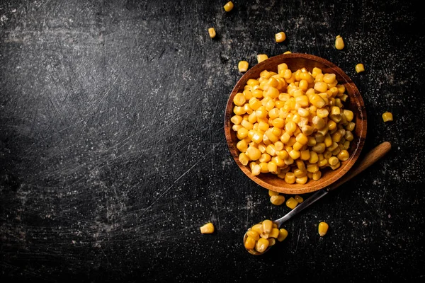 Canned corn on a wooden plate. On a black background. High quality photo