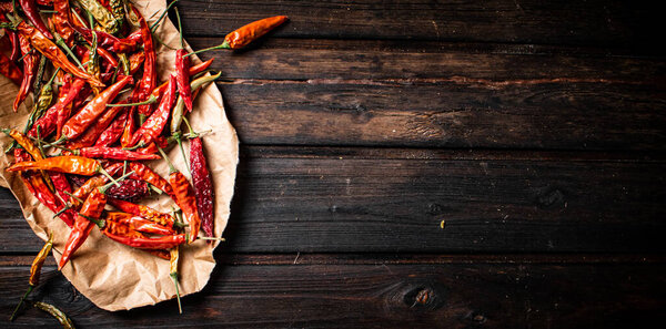 Dried chili peppers on paper. On a wooden background. High quality photo