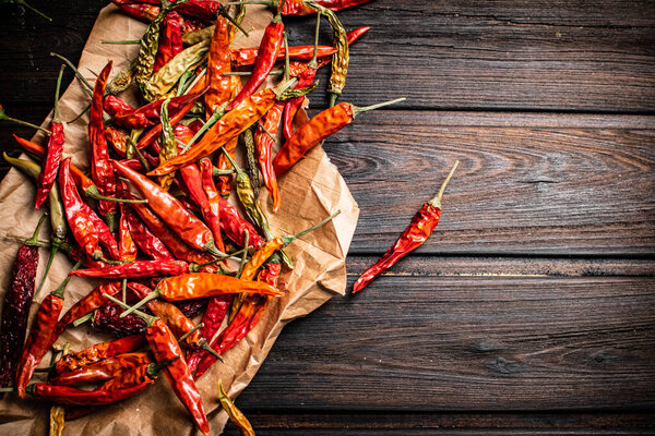Dried chili peppers on paper. On a wooden background. High quality photo