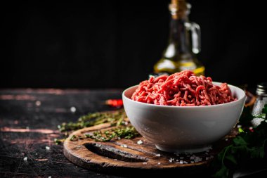 Kesme tahtasındaki kasede kıyma dilimlenmiş et ve kekik. Siyah bir arka planda. Yüksek kalite fotoğraf