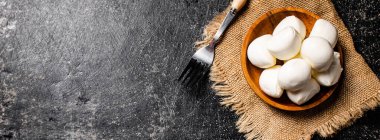 Bir çatalla peçetedeki ahşap tabakta Mozzarella peyniri. Siyah bir arka planda. Yüksek kalite fotoğraf