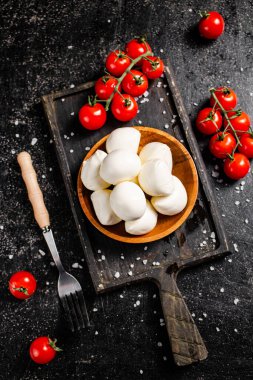 Çeri domatesli dilimleme tahtasındaki Mozzarella peyniri. Siyah bir arka planda. Yüksek kalite fotoğraf