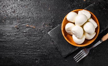 Masadaki ahşap tabakta Mozzarella peyniri. Siyah bir arka planda. Yüksek kalite fotoğraf