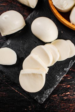 Taş bir tahtanın üzerinde mozzarella peyniri parçaları. Karanlık bir arka plana karşı. Yüksek kalite fotoğraf