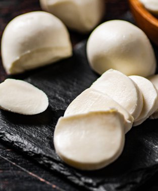 Taş bir tahtanın üzerinde mozzarella peyniri parçaları. Karanlık bir arka plana karşı. Yüksek kalite fotoğraf