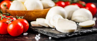 Domatesli bir taş tahtada dilimlenmiş mozzarella. Karanlık bir arka plana karşı. Yüksek kalite fotoğraf