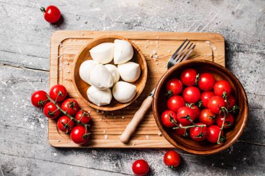 Çeri domatesli ahşap bir tahta üzerinde Mozzarella peyniri. Gri bir arka planda. Yüksek kalite fotoğraf