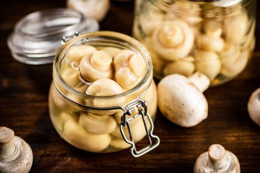 Masanın üzerinde mantar turşusu olan küçük cam bir kavanoz. Ahşap bir arka planda. Yüksek kalite fotoğraf