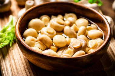 Sebzeli kesme tahtasındaki kasede mantar turşusu. Ahşap bir arka planda. Yüksek kalite fotoğraf