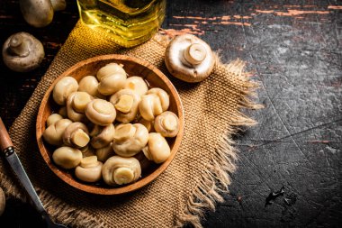 Çuval bezi üzerinde ahşap tabak ve mantar turşusu. Karanlık bir arka plana karşı. Yüksek kalite fotoğraf