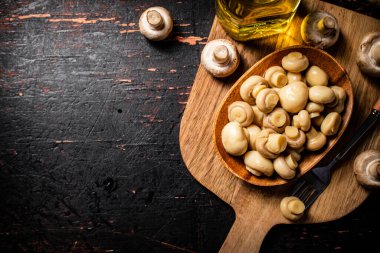 Masadaki ahşap tabakta mantar turşusu. Karanlık bir arka plana karşı. Yüksek kalite fotoğraf